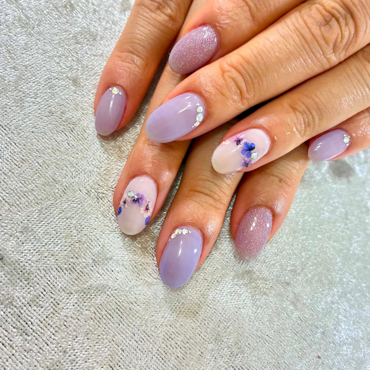 ラベンダーカラーに押し花とストーンをのせたニュアンスジェルネイル